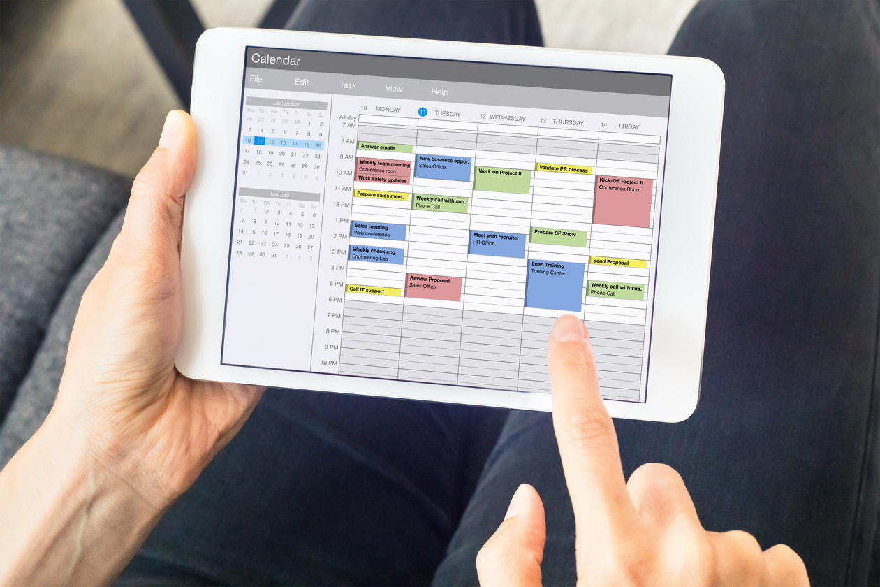 Calendar app on tablet computer with planning of the week with appointments, events, tasks, and meeting. Hands holding device, time management concept, organization of working hours planner, schedule